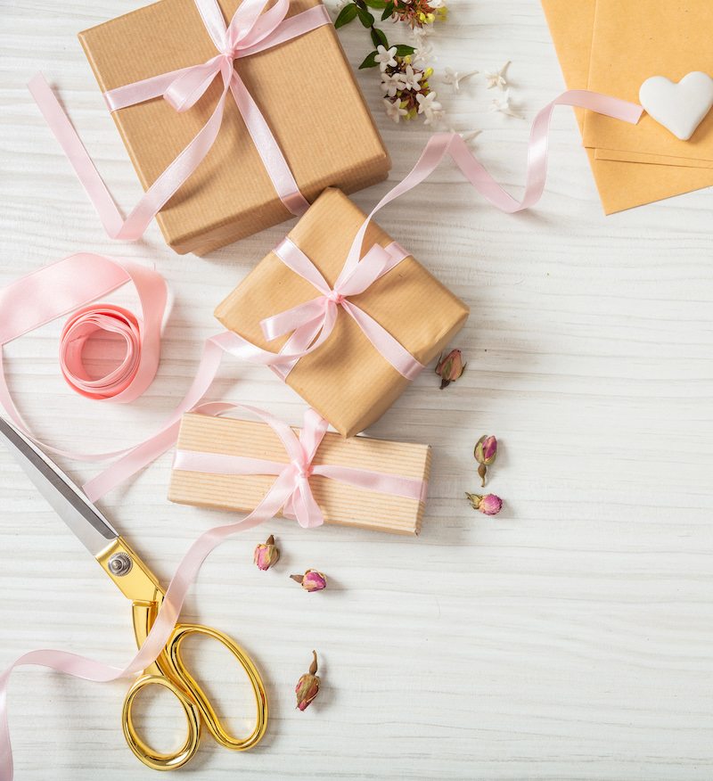 Flat lay and top view of presents and wedding invitations on a white wooden tabletop, copy space.