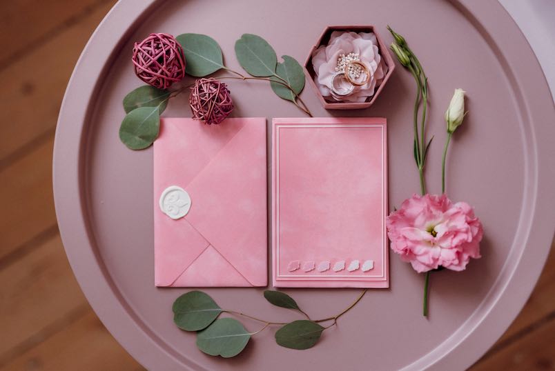 wedding invitation in a gray envelope on a table with green sprigs